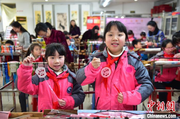 圖為小學生展示繡制好的2022年北京冬奧會吉祥物“冰墩墩”形象?！∮髟屏?攝