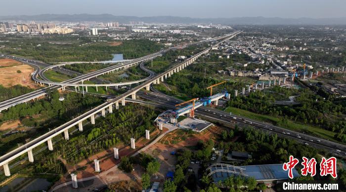 航拍正在建設(shè)的跨越成都繞城高速公路連續(xù)梁施工現(xiàn)場，旁邊依次為已運(yùn)營的成渝高速鐵路和機(jī)場高速公路?！⒅铱?攝