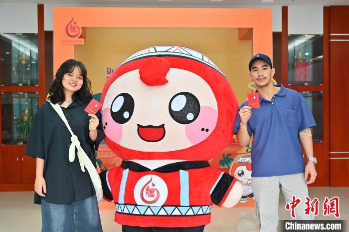 圖為泰國(guó)留學(xué)生手持獻(xiàn)血證與人偶合影?！∮峋?攝