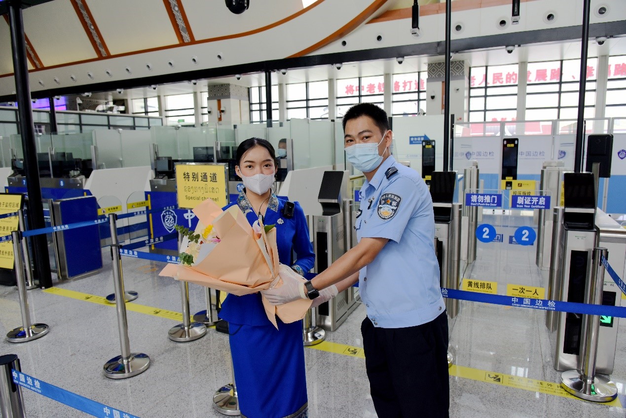 磨憨出入境邊防檢查站民警為中老鐵路第100萬名出入境旅客，D888次國際旅客列車老撾籍乘務(wù)員森達拉·妮緹婭（Sengdala Nitiya），送上鮮花。黃遠飛 攝
