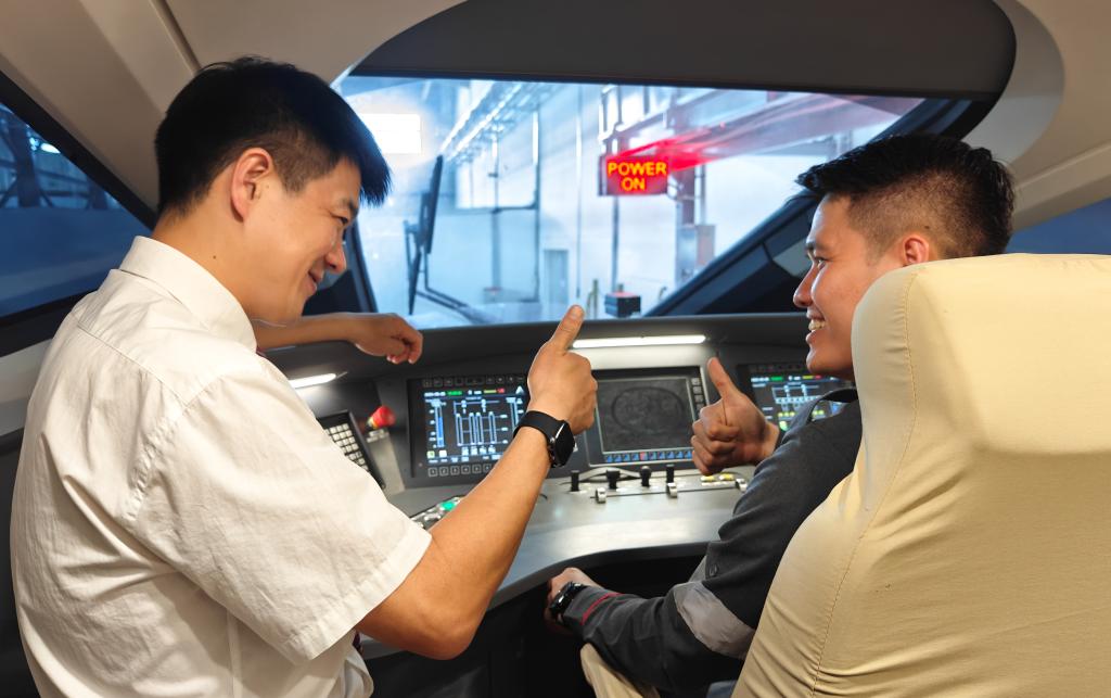 8月25日，在印度尼西亞萬隆的雅萬高鐵德卡魯爾動車所內(nèi)，中國師傅穆振（左）在向印尼火車司機塞蒂亞萬講解動車組出庫前的上電作業(yè)。