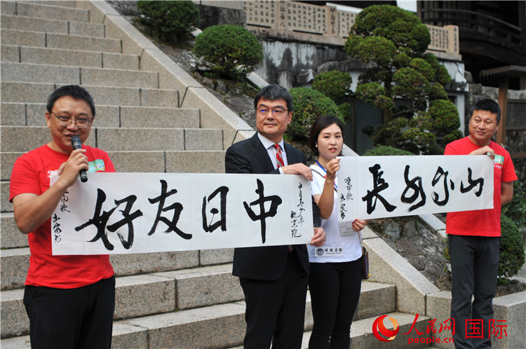 東京中國文化中心主任羅玉泉展示其為本次活動書寫的題詞“中日友好，山高水長”。人民網(wǎng) 蔣曉辰攝