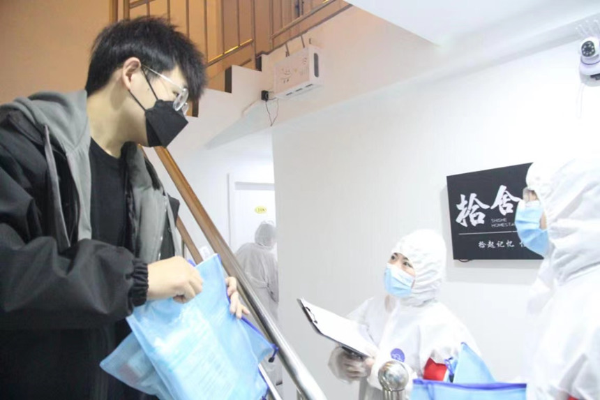 社區(qū)工作人員和志愿者身穿防護(hù)服上門送馬應(yīng)龍大健康防疫包。徐帥攝