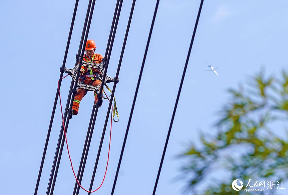 3月11日，在浙江省諸暨市河上鎮(zhèn)，浙江省送變電工程有限公司檢修人員在高空的導(dǎo)線上進(jìn)行線路檢修維護(hù)。人民網(wǎng) 章勇濤攝