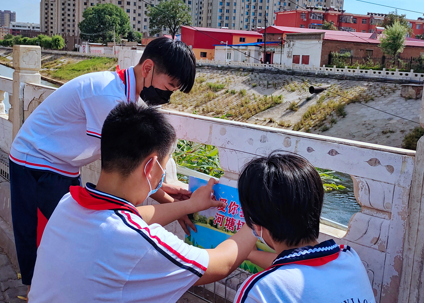 徐水小學(xué)學(xué)雷鋒志愿者在瀑河河邊張貼防溺水警示標(biāo)語。 徐水區(qū)委宣傳部供圖