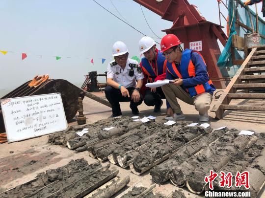 圖為勘察設(shè)計(jì)人員與海事局工作人員查看巖芯情況。　魏震 攝