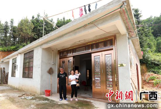 7月4日，在廣西柳州市融安縣大坡鄉(xiāng)崗偉村，脫貧戶肖裕安（左）與妻子、外孫在改造后的房屋前合影。覃慶和 攝