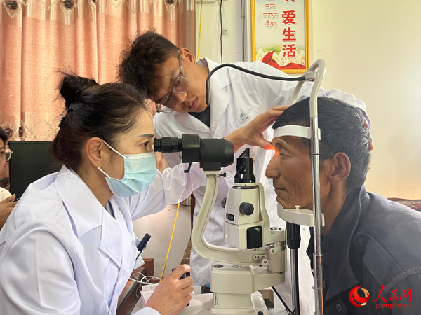 王紅英（左）和團(tuán)隊(duì)成員為達(dá)熱村村民檢查眼睛。人民網(wǎng)記者 杜燕飛攝