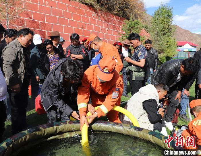圖為森林消防員為護林員講解滅火裝備的使用方法?！〔际猩窒乐ш?供圖