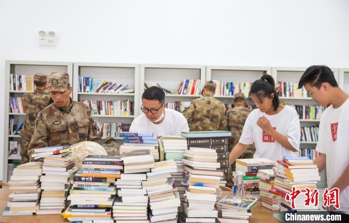 圖為志愿者們和邊防戰(zhàn)士整理圖書。　劉曉東 攝