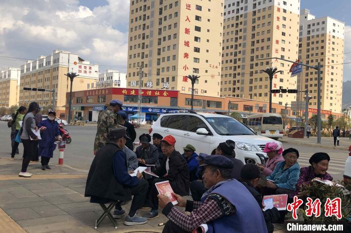 圖為會澤縣城易地扶貧搬遷安置點(diǎn)內(nèi)，老人們聚在廣場上聊天，身后是他們的新家?！】姵?攝