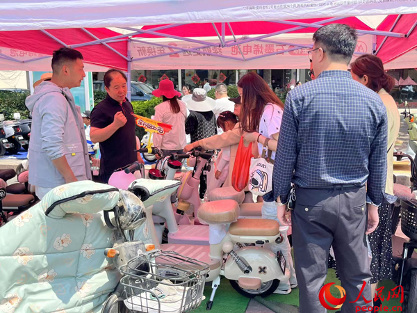 某電動(dòng)自行車品牌工作人員向消費(fèi)者介紹以舊換新相關(guān)情況。人民網(wǎng)記者 杜燕飛攝