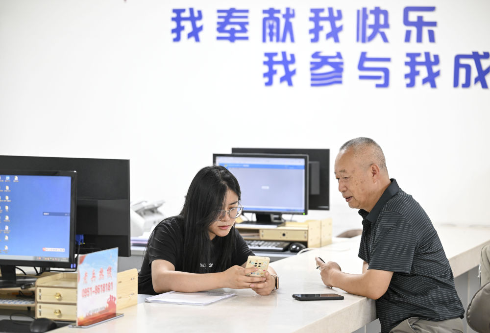 2024年6月20日，在寧夏銀川市金鳳區(qū)長城花園社區(qū)黨群服務(wù)中心，工作人員幫助居民辦理業(yè)務(wù)。圖片來源 新華社