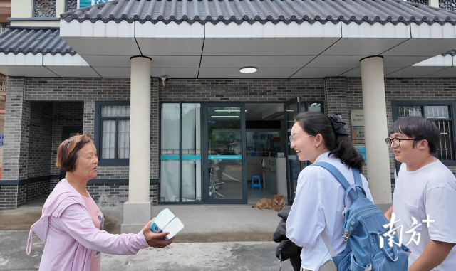 公共服務(wù)組成員王櫻潔（中）和張龍（右）在崖口村衛(wèi)生室前跟村民打招呼。