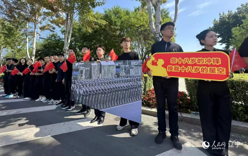 沈陽市人民廣場上，大學(xué)生們手持閱兵的圖片，告慰英烈。人民網(wǎng)記者 周頌雪攝