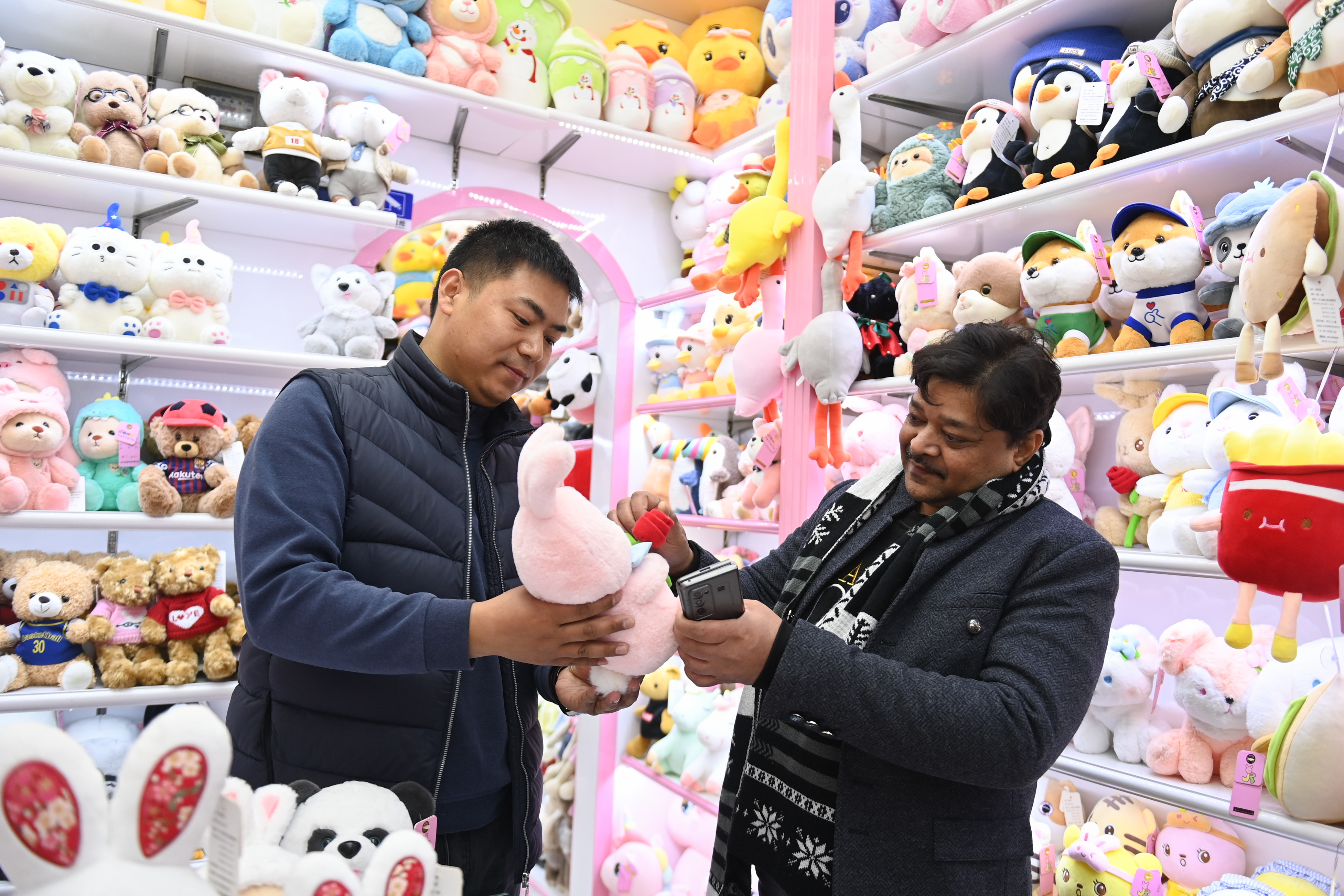 2023年2月2日，來自印度的客商（右）在義烏國際商貿(mào)城的一家玩具店鋪內(nèi)選購。