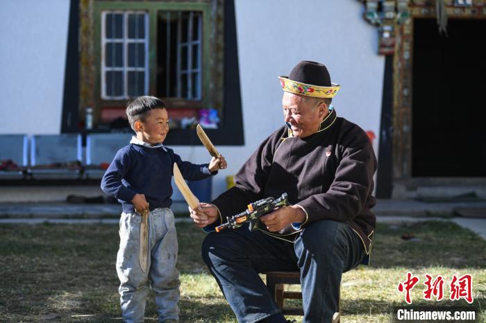 圖為米林縣扎西繞登鄉(xiāng)彩門村64歲的洛桑帶著孫子巴桑在院子的草地上玩耍。　何蓬磊 攝