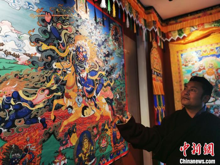圖為久美尖措展示唐卡作品?！?zhí)砀?攝