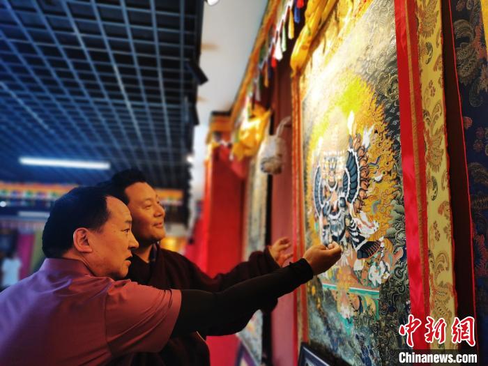 圖為久美尖措展示唐卡作品?！?zhí)砀?攝
