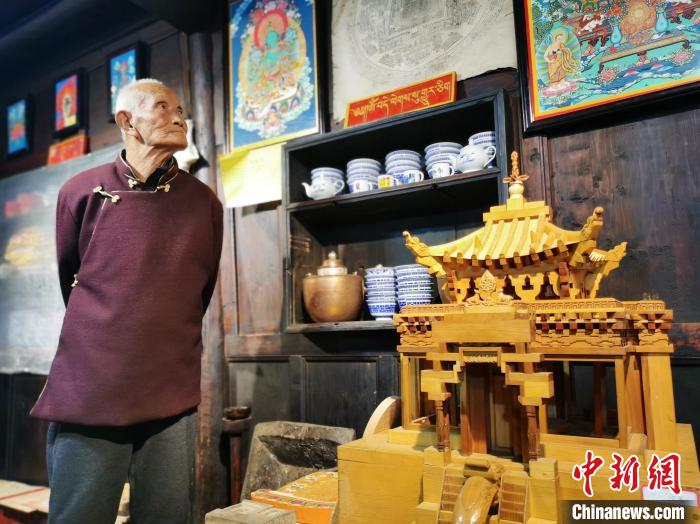 圖為古堡內(nèi)的藝人桑杰展示自己的雕刻作品?！?zhí)砀?攝