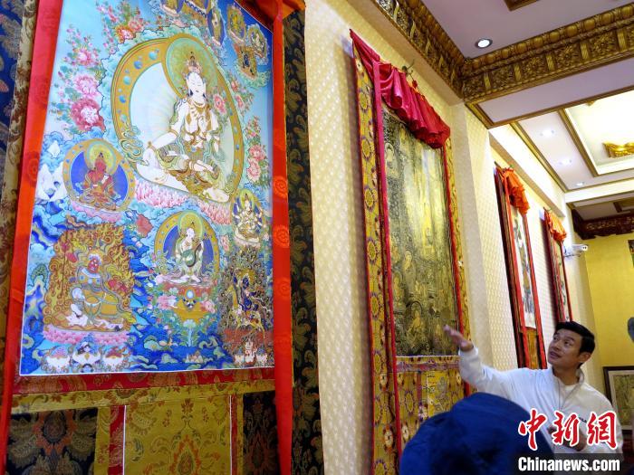 圖為完德尖措展示熱貢龍樹畫苑內的唐卡。　張?zhí)砀?攝