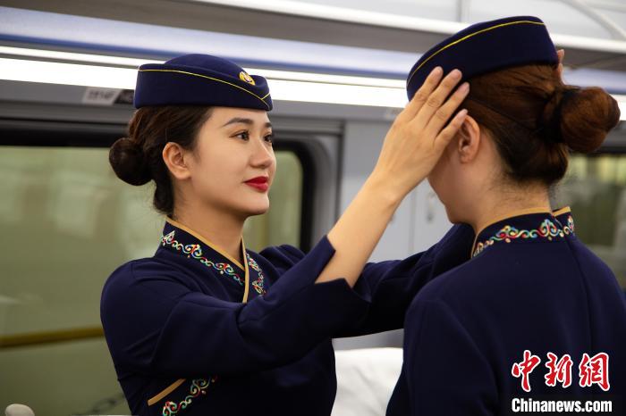 圖為青藏鐵路西格段“復(fù)興號”動車組乘務(wù)員互相整理新制服?！±罾?攝