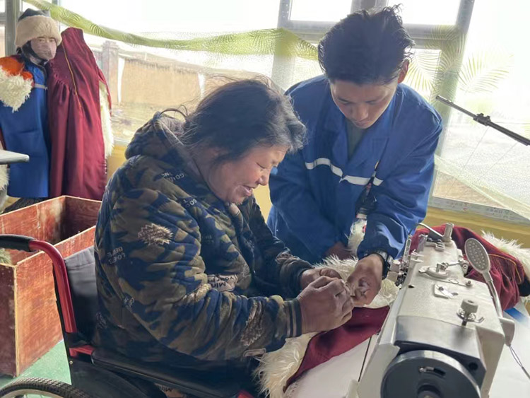 扎西奪爾登幫助殘疾員工裁剪。阿壩州文明辦供圖