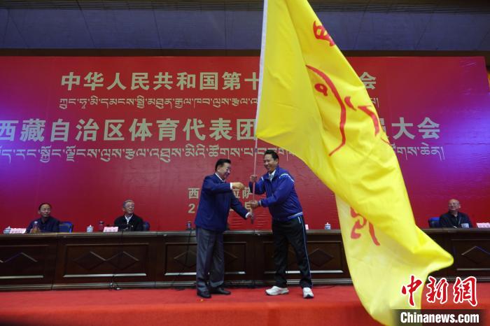 西藏自治區(qū)副主席甲熱·洛桑丹增授代表團團旗，西藏自治區(qū)體育局局長尼瑪次仁接旗。　冉文娟 攝