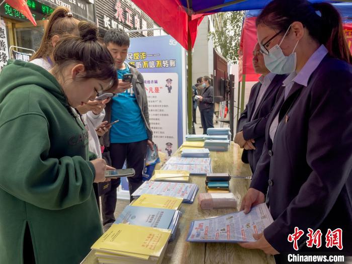 圖為工作人員正在向路過市民介紹國家反詐中心軟件的功能?！≈x牧 攝