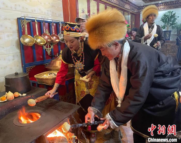 圖為人們在火上烤節(jié)日美食“結(jié)達(dá)”?！∪轿木?攝