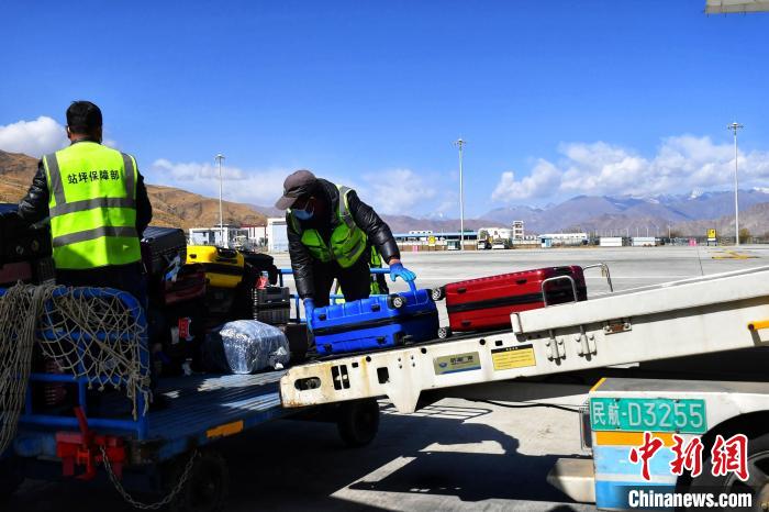 圖為機場工作人員傳送旅客行李箱。　周航 攝