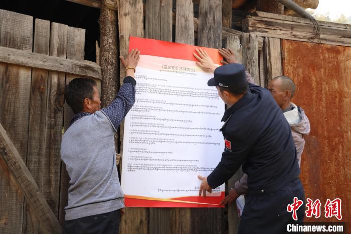 圖為亞?wèn)|邊檢站民警與駐地邊民群眾共同張貼國(guó)家安全知識(shí)教育海報(bào)?！?wèn)|邊檢站 供圖
