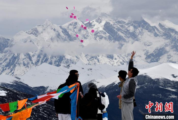 圖為5月14日，游客在西藏林芝色季拉山觀景臺(tái)拋灑“隆達(dá)”(風(fēng)馬旗，藏族民眾的一種祈福方式)?！±盍?攝