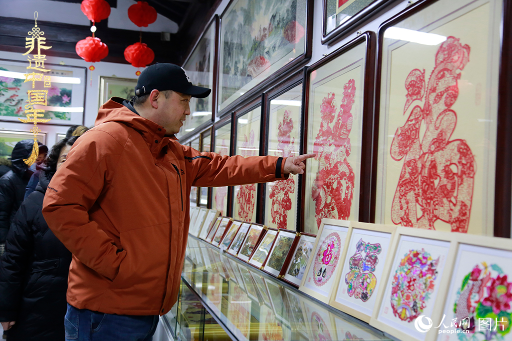 2025年1月23日，游客在天津楊柳青古鎮(zhèn)欣賞傳統(tǒng)剪紙作品，感受指尖上的古老藝術。人民網(wǎng)記者 崔新耀攝